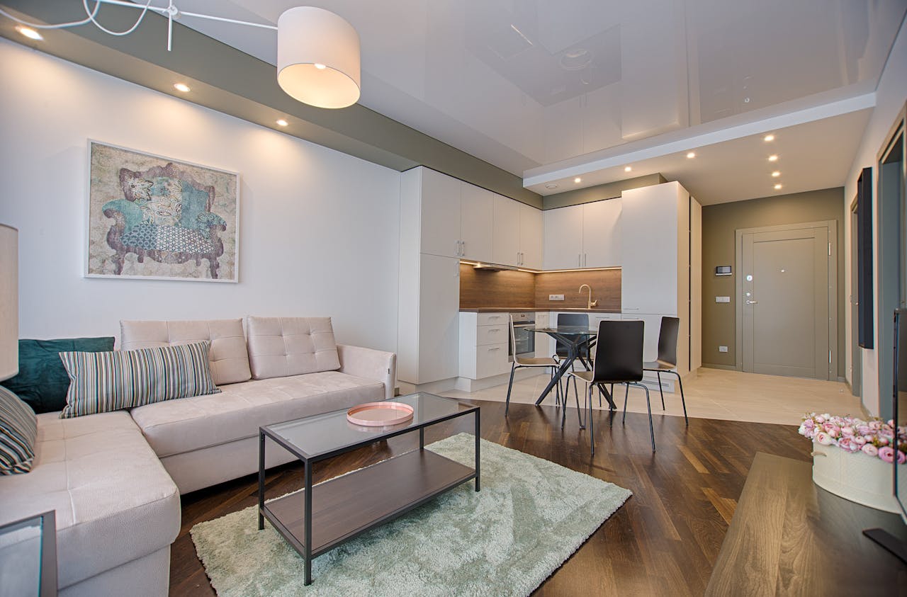 why-choose-us-02 Spacious modern living room featuring chic furniture, stylish decor, and a minimalist kitchen.